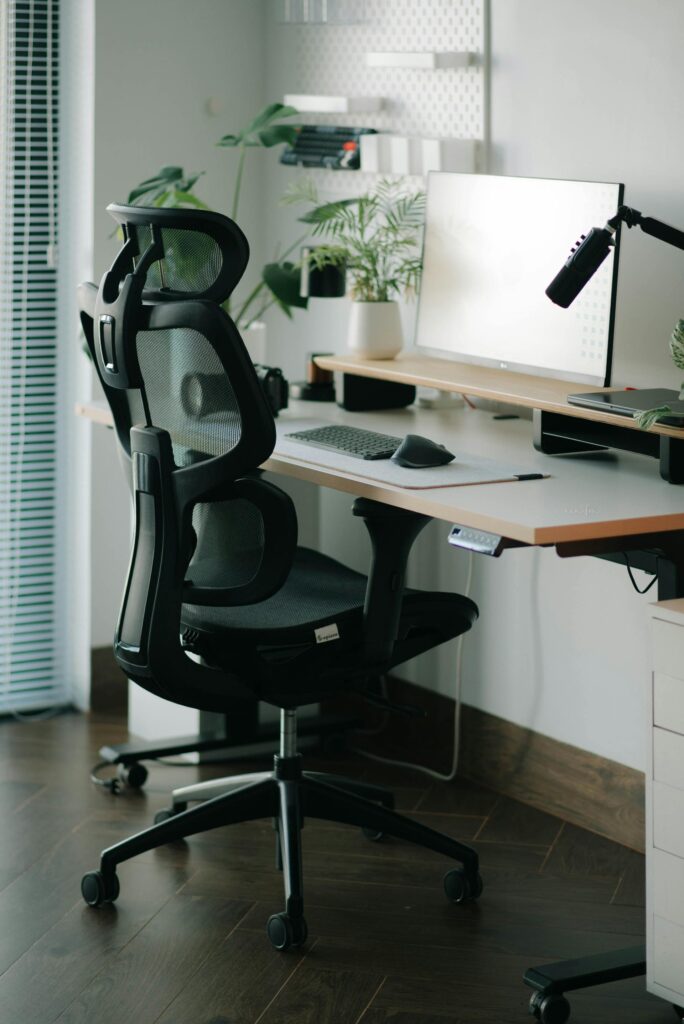 Chaise ergonomique noire devant un bureau moderne avec plante verte